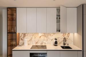 una cocina con armarios blancos y fregadero en Beautiful Designer Apartment in Riga center en Riga