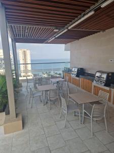um pátio com mesas e cadeiras e o oceano em Apartamento cerca a la Playa em Gaira
