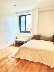 a white bedroom with a bed and a window at Delancey Tower in Jersey City