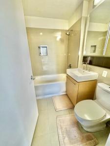 a bathroom with a toilet and a sink and a tub at Delancey Tower in Jersey City