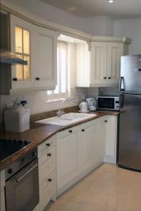 a kitchen with white cabinets and a sink and a refrigerator at MacKenzie Lodge in Lahinch