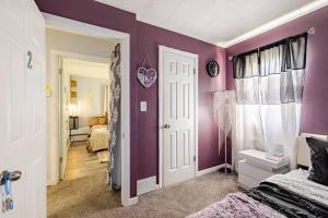 sypialnia z fioletowymi ścianami, łóżkiem i drzwiami w obiekcie Elegant Serene Escape in Wyandotte 