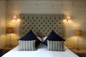a bedroom with a bed with blue pillows and two lamps at MacKenzie Lodge in Lahinch