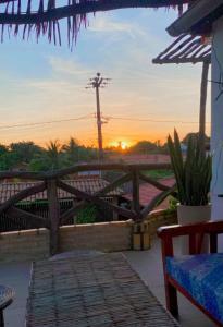 um pôr-do-sol a partir de um pátio com uma ponte de madeira em Pousada Villa Mariposa em Beberibe