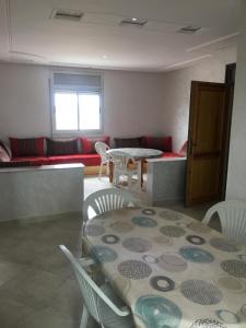 een woonkamer met een tafel en stoelen en een bank bij Appartement Plage & Famille in Ras El Ma