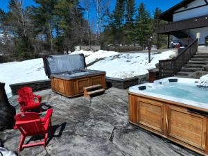 un jacuzzi en un patio con sillas rojas en Innsbruck Inn at Stowe en Stowe