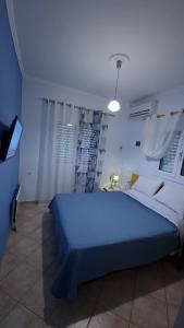 a bedroom with a blue bed and a television at Relaxing Country house Porto Vito in Aigosthena