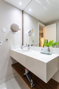 ein Badezimmer mit einem weißen Waschbecken und einem Spiegel in der Unterkunft Maximus Luxury in Wyn Berrini - WTC in São Paulo