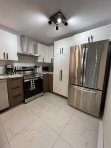 a kitchen with white cabinets and a stainless steel refrigerator at Luxueuse Villa, Unique en ville in Drummondville