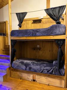 two bunk beds in a room with blue sheets at Hostel Cosmo in El Bolsón