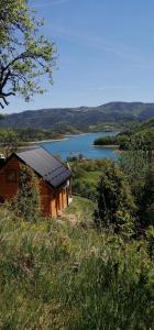 Vila Bella, Tara, Zaovinsko jezero في Zaovine: منزل صغير على تلة بجوار بحيرة