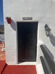 um edifício branco com uma porta preta e um candeeiro em B&B Los Lujos em Oria