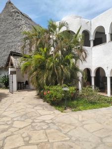 een gebouw met palmbomen en een patio bij MARIA the Star on the Sea Beach cottages, cottage Mama in Malindi