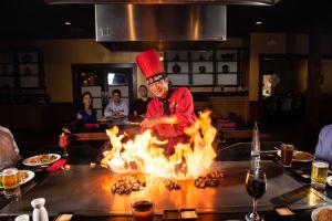 un chef cocinando sobre un fuego en una cocina en Mai Hana Hotel, en Orlando