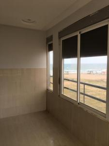 een lege kamer met 2 ramen en uitzicht op de oceaan bij Appartement Plage & Famille in Ras El Ma