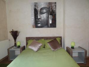 ポマールにあるCes Jours À Pommardのベッドルーム1室(緑のベッド1台、壁に彫像付)