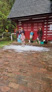 a little girl standing in front of a red building at Mlýn u skály in Deštné v Orlických horách