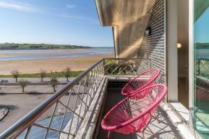 una silla rosa sentada en un balcón con vistas a la playa en Hotel Milagros Golf, en Mogro