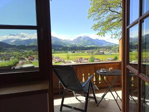a chair on a balcony with a view of the mountains at Apartment Sonnenwinkl in Kössen