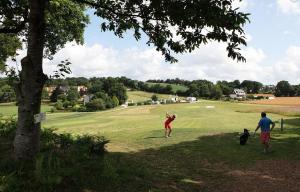 two people and a dog standing on a golf course at Le Coin Cozy in Carhaix-Plouguer
