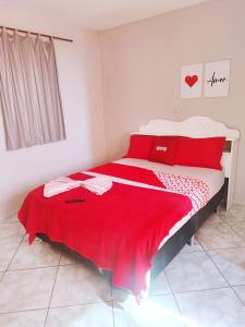 a bedroom with a large bed with red sheets at Hotel Ita in Itaboraí