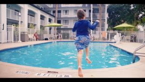 un niño pequeño saltando a una piscina en Mai Hana Hotel, en Orlando