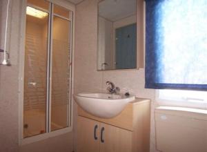 a bathroom with a sink and a glass shower at Mobilhome Vieux Boucau les bains in Vieux-Boucau-les-Bains