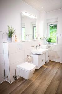 a white bathroom with a toilet and a sink at Seeblick in Stuer