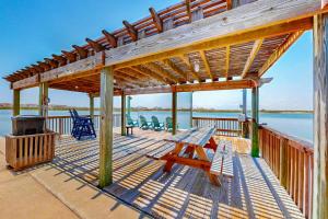una terraza de madera con un banco de picnic y una parrilla en Lakeshore Villas, en Corpus Christi