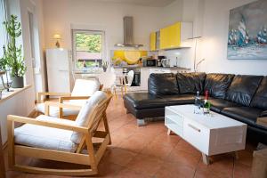 a living room with a black leather couch and a kitchen at Seeblick in Stuer