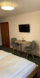 Zimmer mit einem Tisch, 2 Stühlen und einem TV in der Unterkunft Rheinischer Hof in Duisburg