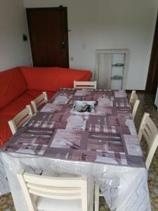 una mesa cubierta de plástico con sillas y un sofá en Appartamento dei Pavoni, en Punta Marina