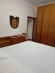 1 dormitorio con cama blanca y espejo en Appartamento dei Pavoni, en Punta Marina