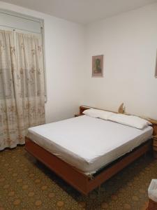 1 dormitorio con 1 cama con sábanas blancas y ventana en Appartamento dei Pavoni, en Punta Marina