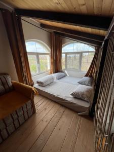 a large bed in a room with two windows at Vikendica Smokvica in Sremski Karlovci