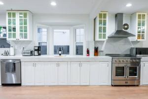 una cocina con armarios blancos y electrodomésticos de acero inoxidable en Villa Palo Alto, en East Palo Alto