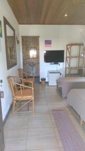 a living room with a bed and a tv in a room at Pousada Vila Imbassai in Imbassai