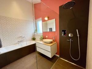 ein Badezimmer mit einem Waschbecken, einer Badewanne und einer Dusche in der Unterkunft Spacieuse maison avec jardin in Savagnier