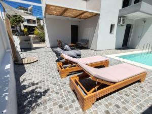 a patio with lounge chairs and a swimming pool at Amphitrite Beach House in Agios Nikolaos