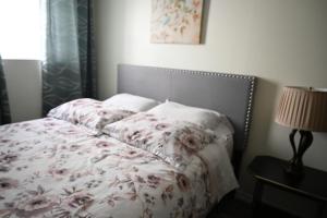 1 dormitorio con 1 cama con manta de flores y lámpara en Metropolitan Suite, en Niagara Falls