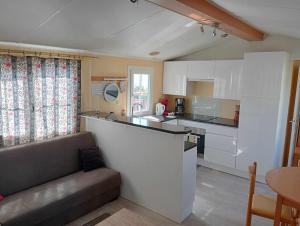 a kitchen with white cabinets and a couch in a room at Casa da Cristina 5A in Burinhosa