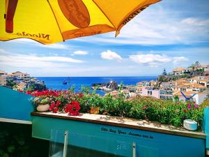 a view of the ocean from a balcony with an umbrella at ATTIC BAY - Cozy Stay with Sea View in Câmara de Lobos
