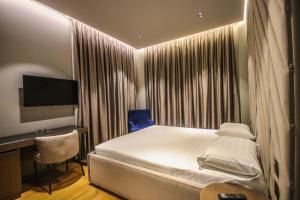a bedroom with a bed and a desk and a television at Atrium Hotel in Tirana