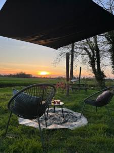 twee stoelen en een tafel in een veld met zonsondergang bij PipowagenTwente in Lattrop