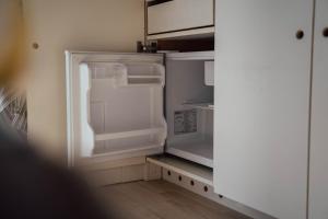 een lege koelkast met de deur open in een keuken bij PipowagenTwente in Lattrop