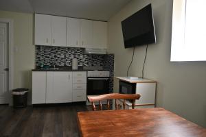 a kitchen with white cabinets and a table and a television at Metropolitan Suite in Niagara Falls