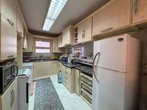 a kitchen with a white refrigerator and wooden cabinets at 3BR Apartment on Plage in Dawwār ‘Abd Allāh