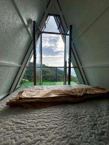 a bed in a room with a large window at Glamping La Mardo in Cartago