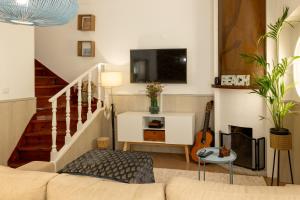 a living room with a couch and a tv at Elisabeth Holidays House in Costa da Caparica