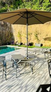 - un groupe de tables et un parasol à côté d'une piscine dans l'établissement A CASA DI LAURENA piscine chauffée proche St Florent, à Vallecalle